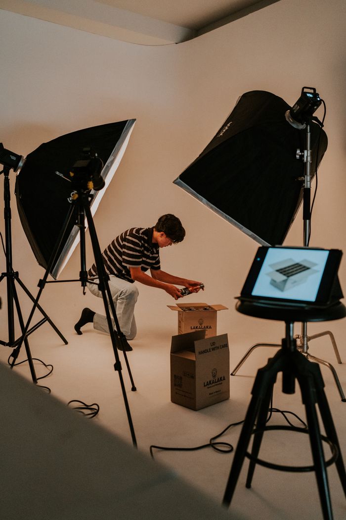 services-03 A man prepares an unboxing video in a professional studio with lights and tablet.