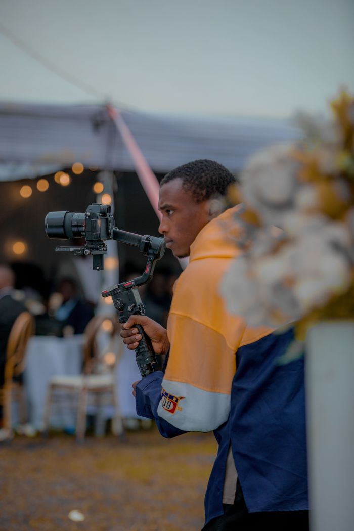 services-10 A videographer with camera gimbal filming an event setup outdoors.