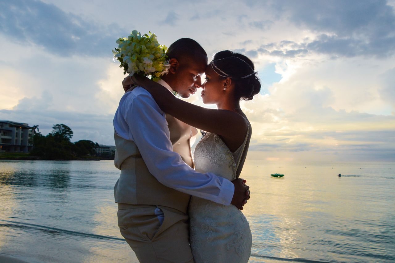 services-08 A loving couple embraces on the beach at sunset, celebrating their wedding by the sea.